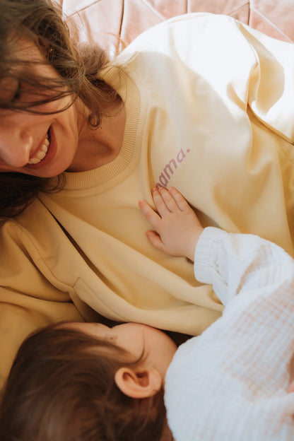 Dłoń dziecka na lawendowym napisie mama. na bananowej bluzie do karmienia Melanie