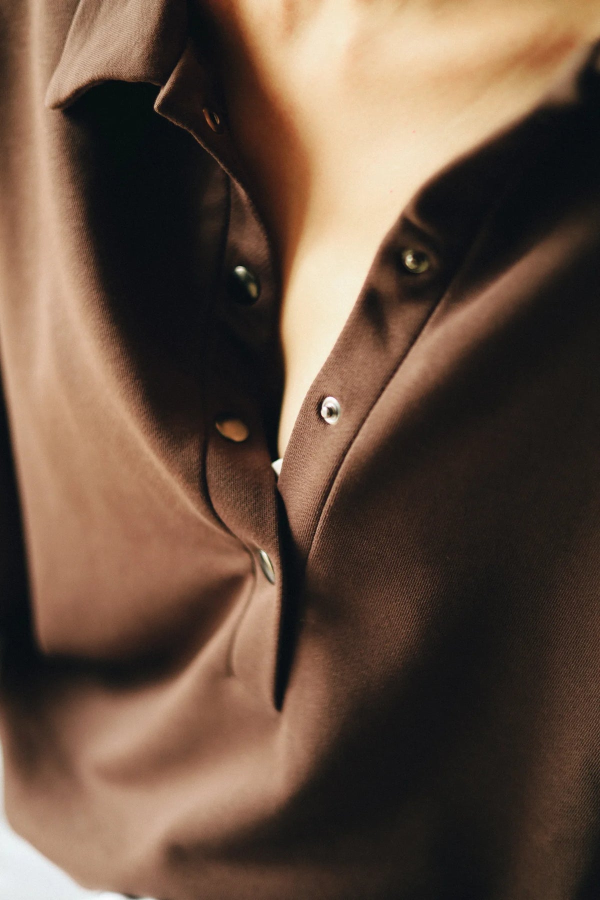 Zbliżenie na rozpięte zatrzaski czekoladowej bluzy polo do karmienia