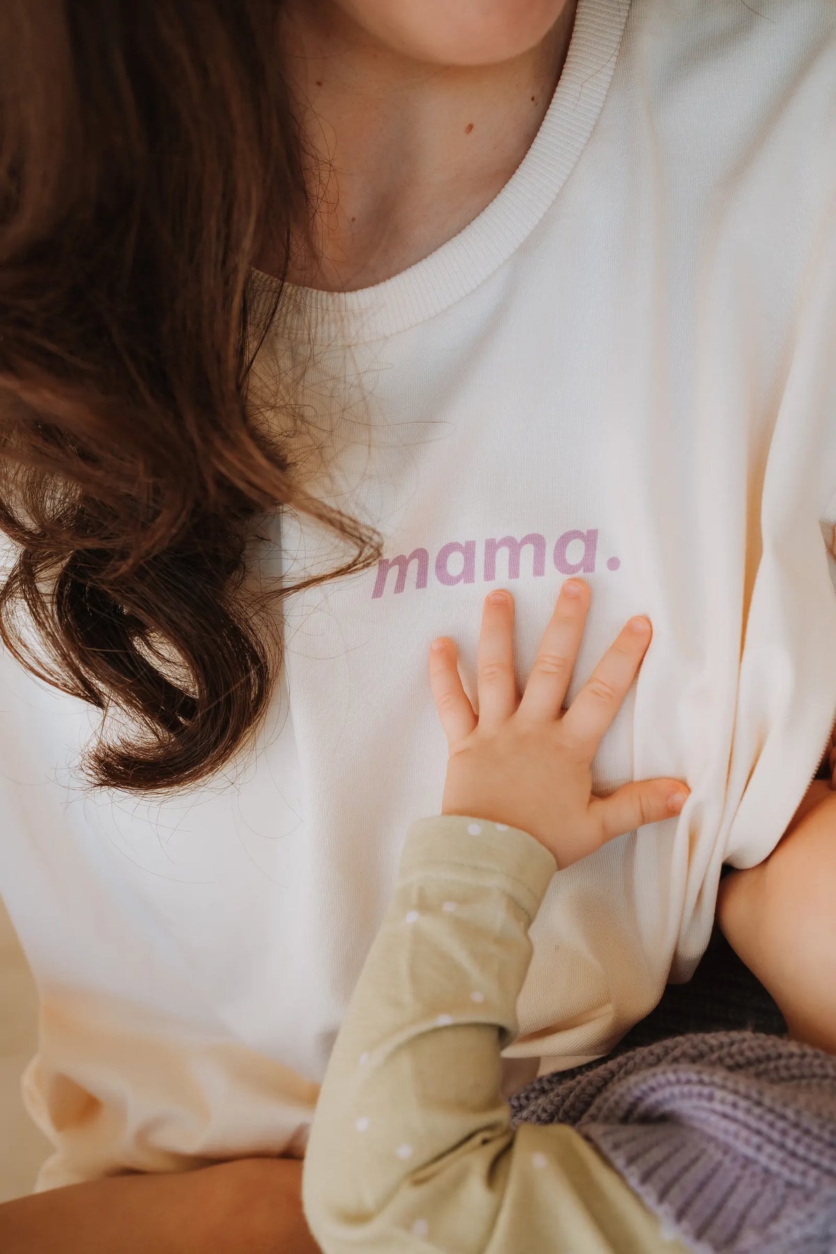 Dłoń dziecka na koszulce do karmienia z nadrukiem mama. w kolorze coconut, zbliżenie