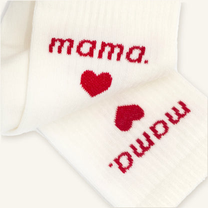 Zbliżenie na czerwony napis mama. i serduszko wpleciony w prążkowany ściągacz kremowych skarpetek