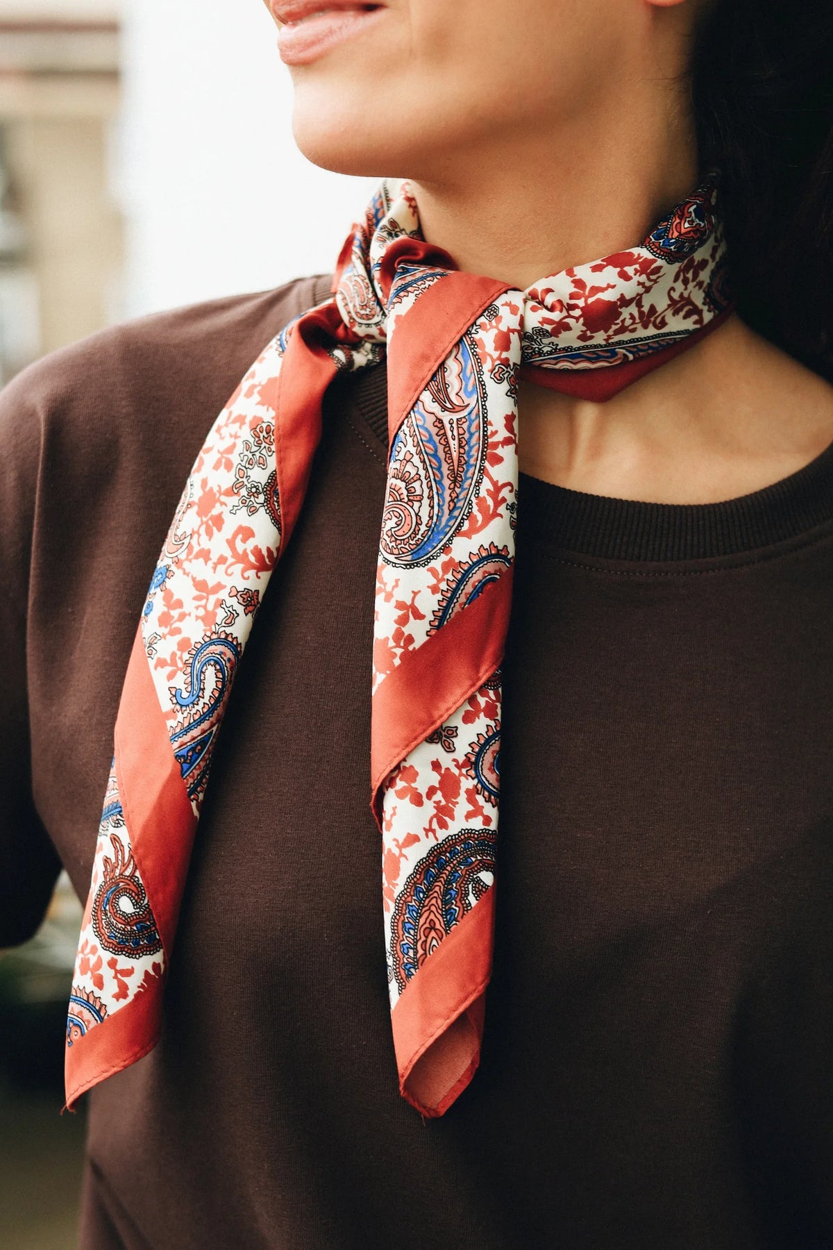 Zbliżenie na dekolt ze ściągaczem czekoladowego t-shirtu Helen i apaszkę w paisley zawiązaną pod szyją