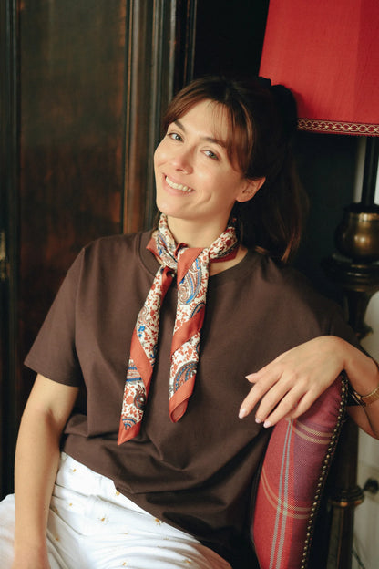Uśmiechnięta kobieta w czekoladowym t-shircie do karmienia Helen z apaszką siedzi na fotelu