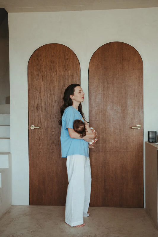 Mama w niebieskim t-shircie do karmienia oversize Ciao Ragazza trzyma niemowlę na rękach