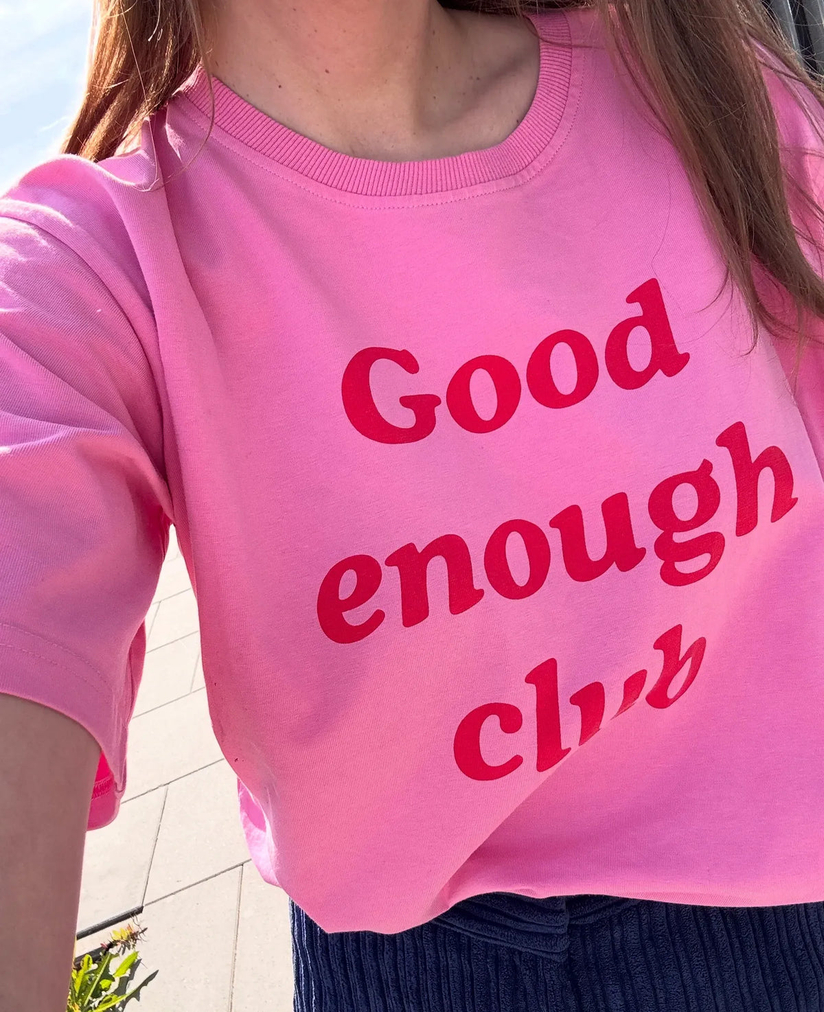 Zbliżenie na czerwony napis Good enough club na różowym t-shircie do karmienia z dekoltem ze ściągaczem